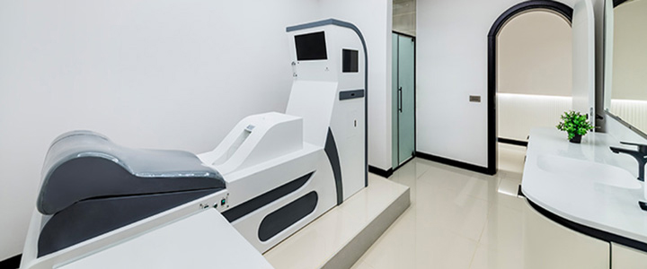 Heller Behandlungsraum von Medworld mit schwarzen Akzenten; im Fokus eine weiß graue Liege.